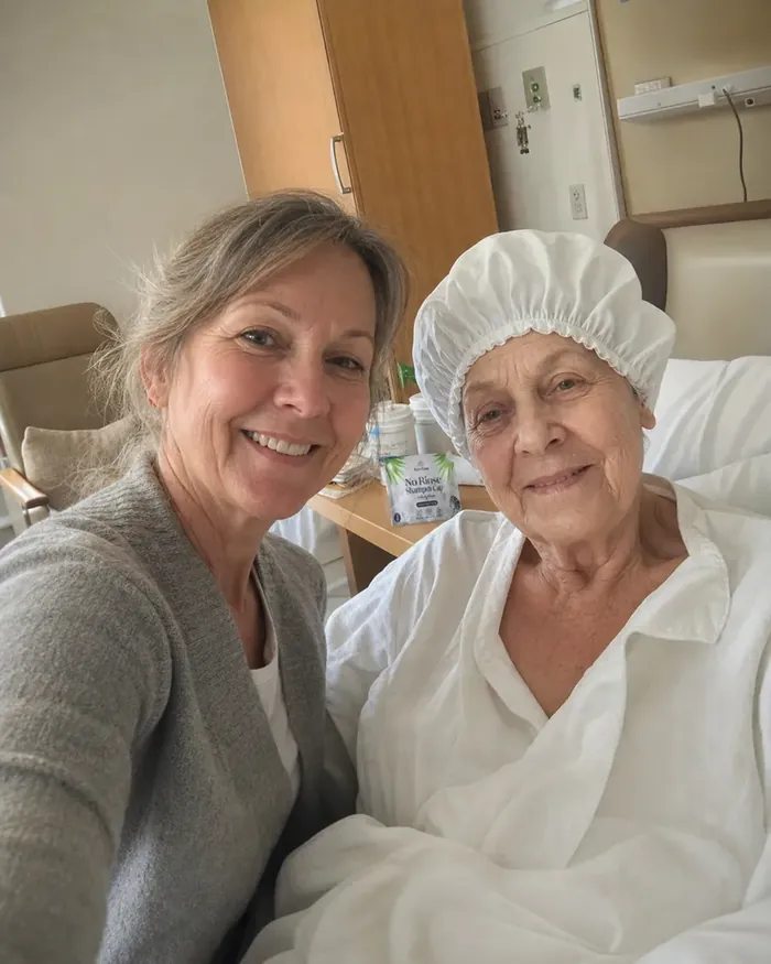 Daughter taking a selfie with her elderly mother in a hospital bed wearing a PureEase shampoo cap